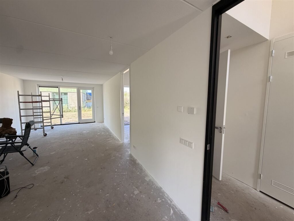 Doorzonwoonkamer van een nieuwbouwwoning met strak afgewerkte wanden