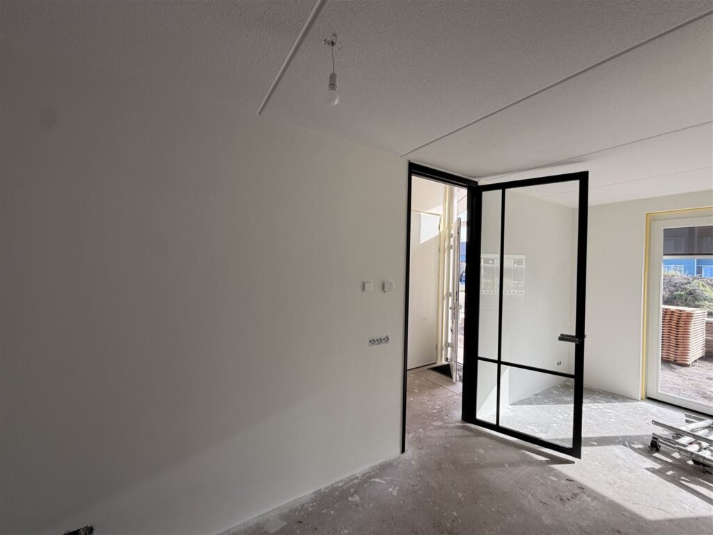 Kamer met stalen binnendeur en strak afgewerkte witte wanden