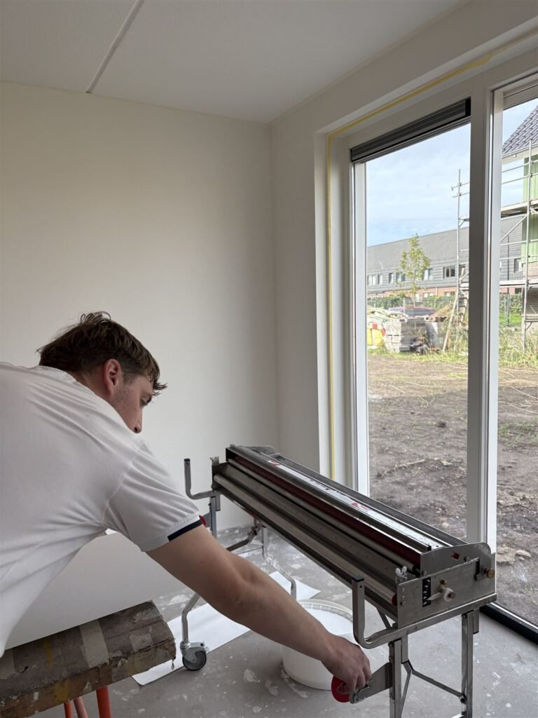 Werkplek met inlijmmachine in een lege nieuwbouwkamer met tuindeuren