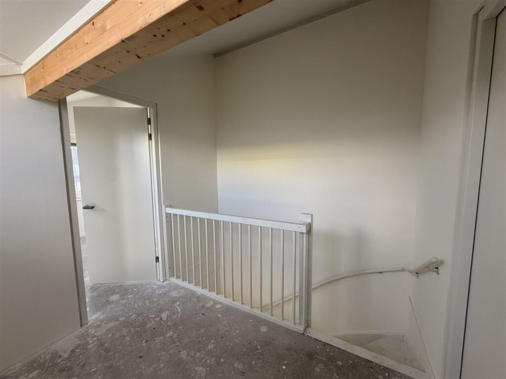 Overloop met trapgat en witte trapleuning, de wanden afgewerkt met glasweefselbehang