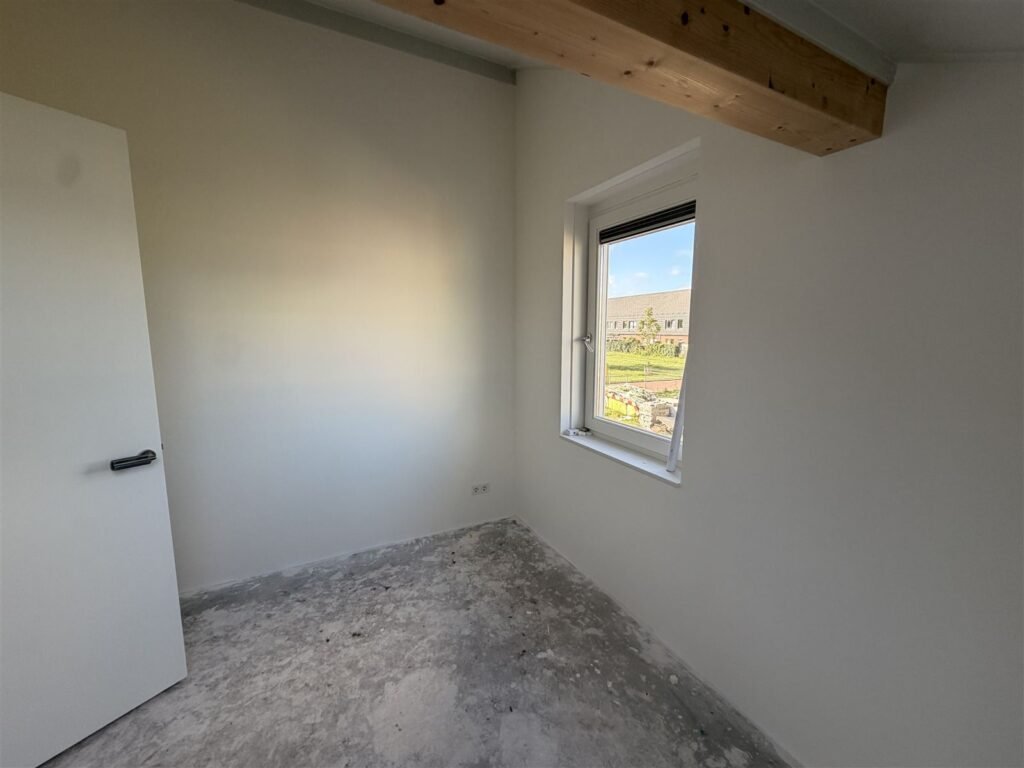 Slaapkamer met houten balk en raam, de wanden afgewerkt in het wit