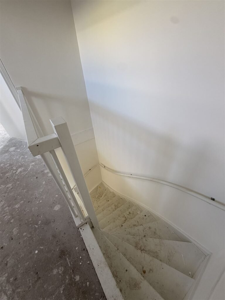 Trapgat van een nieuwbouwwoning met afgewerkte wanden langs de trap