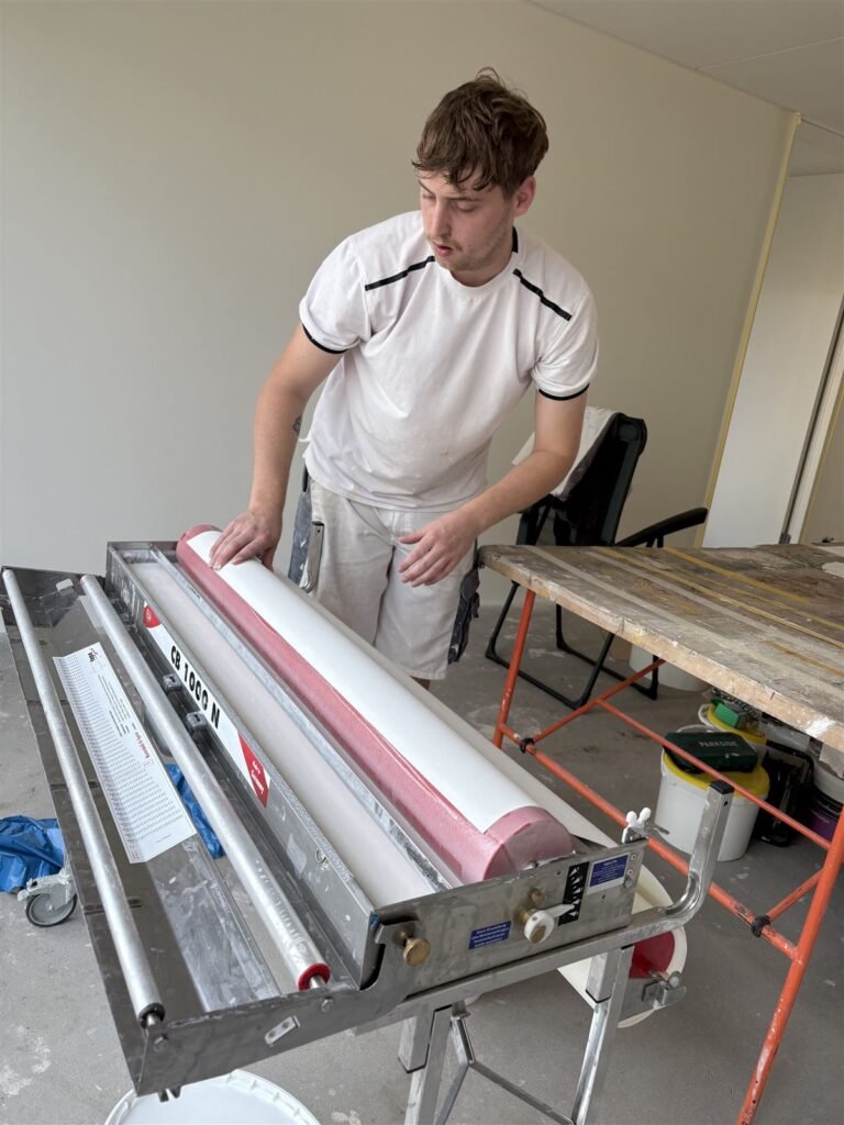 Behanger van Bouwsector Nederland bereidt de rollen glasweefsel voor op de inlijmmachine