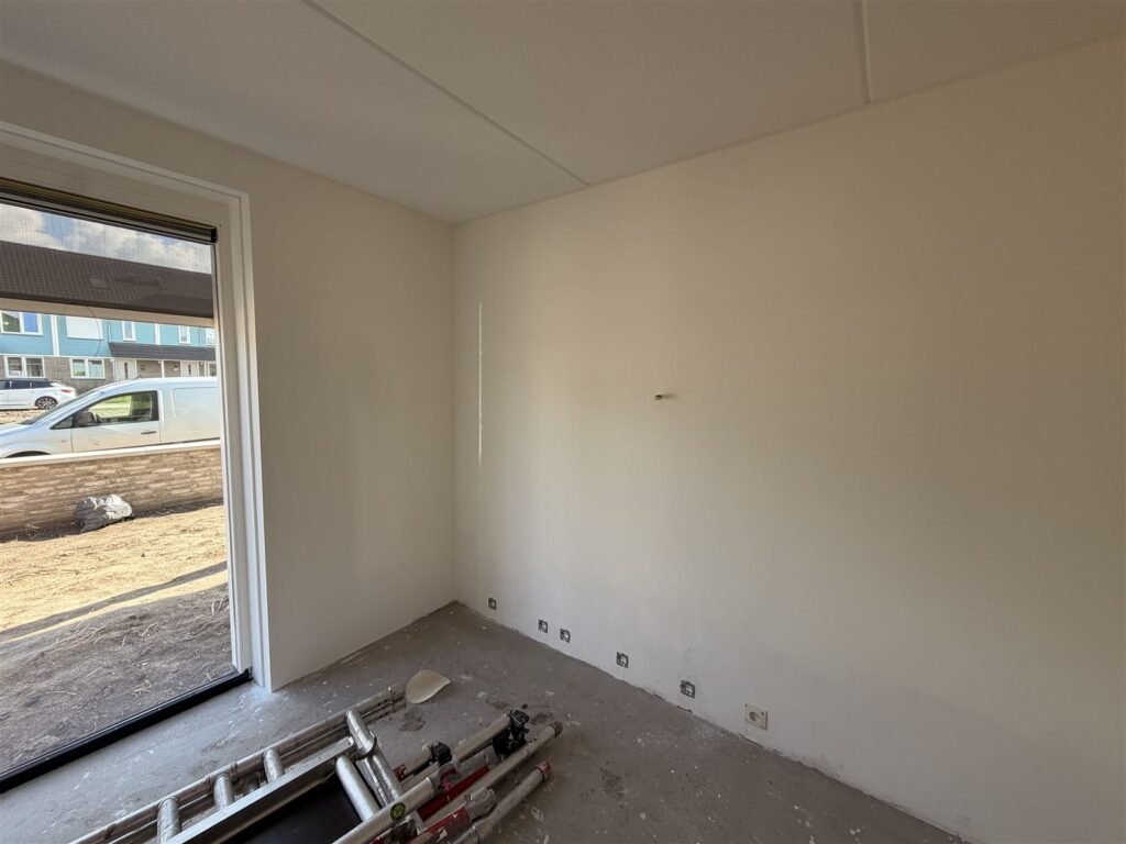 Witte wand met groot raam in een nieuwbouwwoning na het behangen