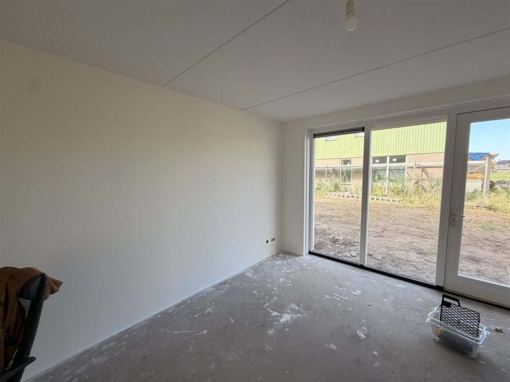 Nieuwbouwwoonkamer met schuifpui en egaal witte wanden na het behangen