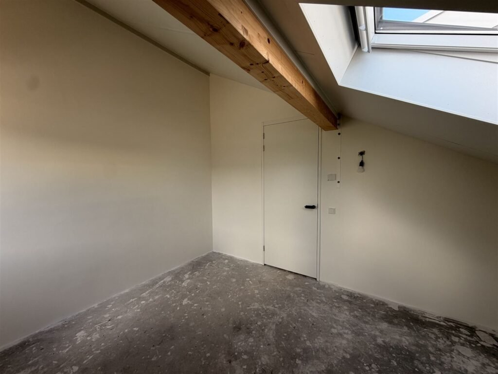 Zolderkamer met deur en schuine wand na het sauzen
